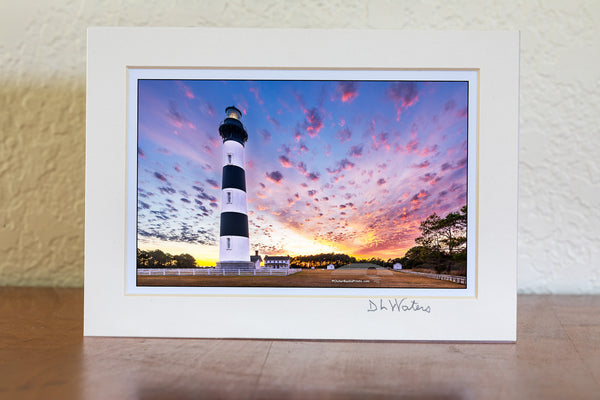 Bodie Island Lighthouse at Sunset: A Beacon Beneath Cotton Candy Skies. This stunning scene captures the magic of the Outer Banks, where history and nature blend seamlessly.
Interesting Facts About Bodie Island Lighthouse:
	1.	Third Time’s the Charm: The current Bodie Island Lighthouse is the third built on this site. The first one was abandoned due to structural issues, and the second was destroyed during the Civil War.
	2.	Height and Reach: Standing at 156 feet, the lighthouse’s first-order Fresnel lens