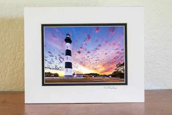 Bodie Island Lighthouse at Sunset: A Beacon Beneath Cotton Candy Skies. This stunning scene captures the magic of the Outer Banks, where history and nature blend seamlessly.
Interesting Facts About Bodie Island Lighthouse:
	1.	Third Time’s the Charm: The current Bodie Island Lighthouse is the third built on this site. The first one was abandoned due to structural issues, and the second was destroyed during the Civil War.
	2.	Height and Reach: Standing at 156 feet, the lighthouse’s first-order Fresnel lens