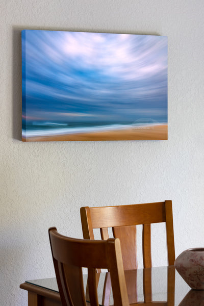 Using my wide-angle lens and tilting the camera up to include mostly sky I swung the camera down the beach keeping the horison level during the 1/10 of a second exposure. This camera technique is known as ICM photography or intentional camera movement photography. Distortion from tilting the 16 mm wide angle lens up created this circular affect. This photo was taken in the Cape Hatteras National Seashore in the Outer Banks of NC.