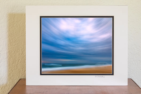 Using my wide-angle lens and tilting the camera up to include mostly sky I swung the camera down the beach keeping the horison level during the 1/10 of a second exposure. This camera technique is known as ICM photography or intentional camera movement photography. Distortion from tilting the 16 mm wide angle lens up created this circular affect. This photo was taken in the Cape Hatteras National Seashore in the Outer Banks of NC.