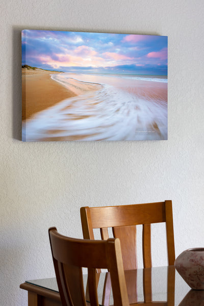 Sunrise with sweping wave at Cape Hatteras National Seashore on the Outer Banks, NC. While watching the waves ebb and flow I envisioned this photo. I knewI wanted the empty beach with the spectacular early morning light on the clouds as the sea foam swept back out to sea with a long enough shutter speed to show the motion.
