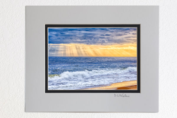 8 x 10 luster print in a 11 x 14 ivory and black double mat of Sun rays breaking through a stormy sky over the beach on the Outer Banks.