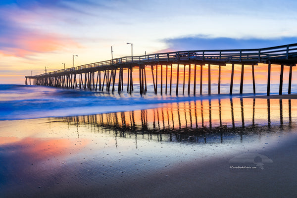 Nags Head Fishing Pier at sunrise reflected in the wet sand beach on the Outer Banks of NC.