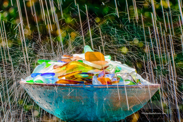 This beach glass was found on the beaches of the Outer Banks. It is just a small part of our collection. Broken bottles are smoothed and tumbled by the surf and sand before it becomes sea glass. I photographed this in my backyard using an oscillating sprinkler.The slow shutter speed and back light made of the sprinkler look like raindrops.