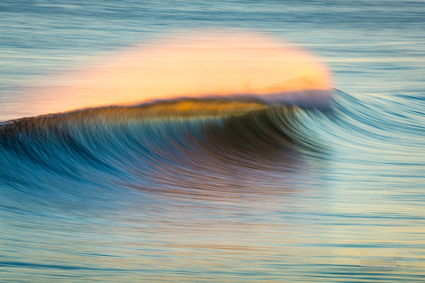 Sunrise windblown surf spray at Kitty Hawk Pier photographed with a long telephoto lens and a slow shutter speed.