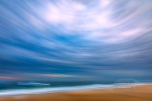 Using my wide-angle lens and tilting the camera up to include mostly sky I swung the camera down the beach keeping the horison level during the 1/10 of a second exposure. This camera technique is known as ICM photography or intentional camera movement photography. Distortion from tilting the 16 mm wide angle lens up created this circular affect. This photo was taken in the Cape Hatteras National Seashore in the Outer Banks of NC.