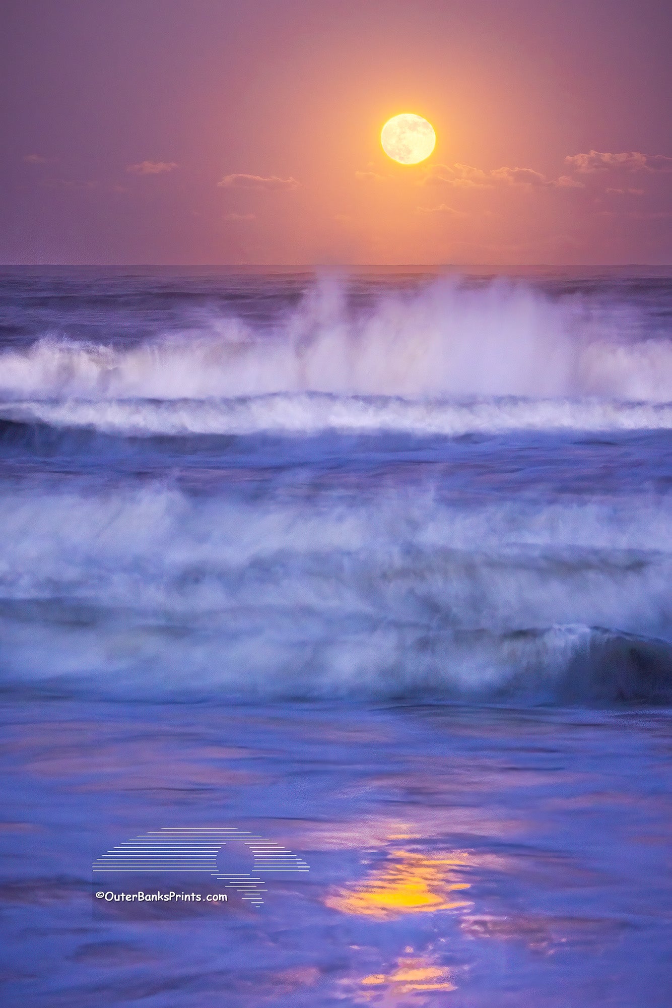 A nearly full moon photographed at twilight with a 1.3-second exposure beautifully captures the movement of the waves and the reflection of the moonlight in Kitty Hawk, located in the Outer Banks of North Carolina.