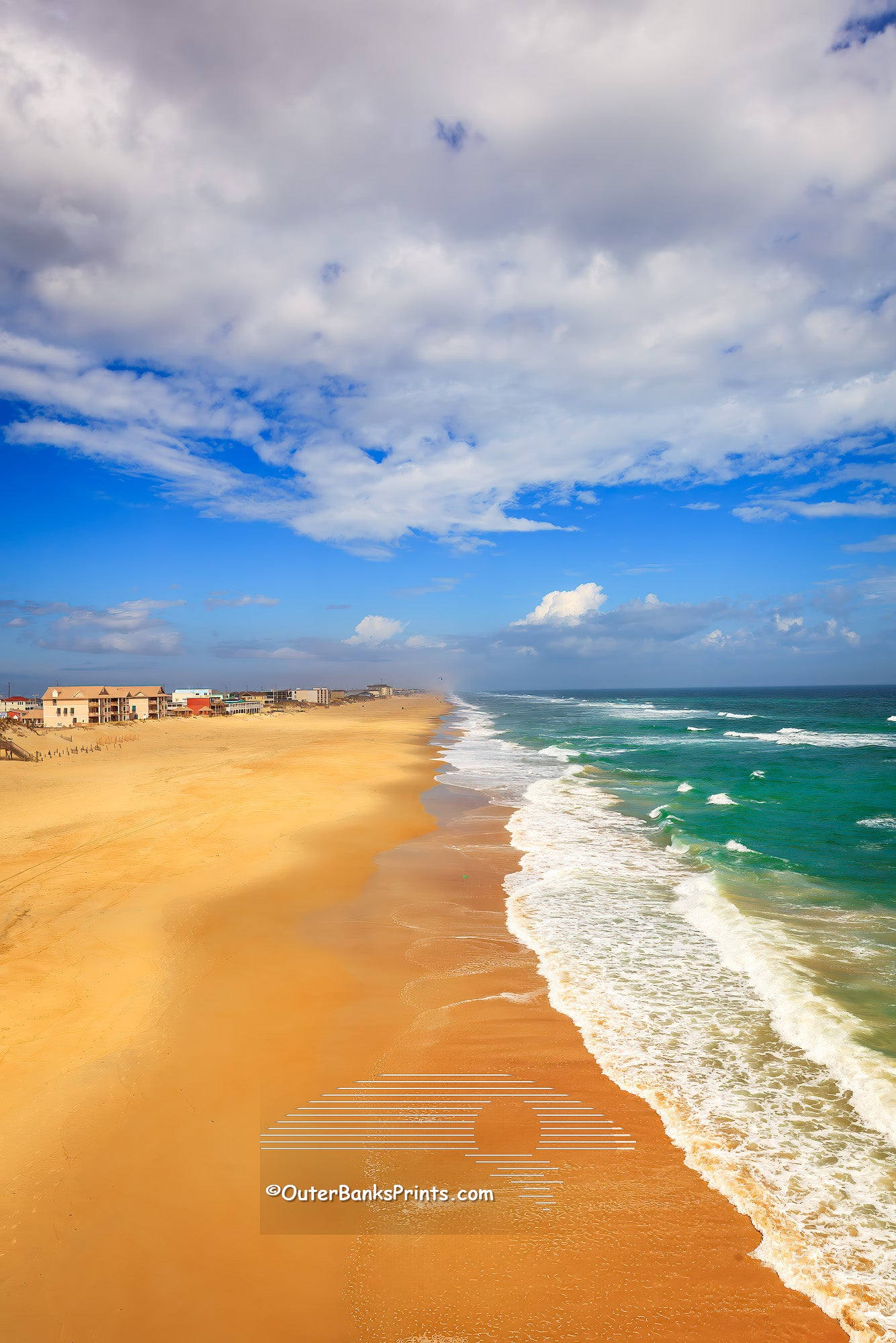 Photograph of Nags Head beach taken from Jennette's Pier on a sunny day with scattered clouds.
