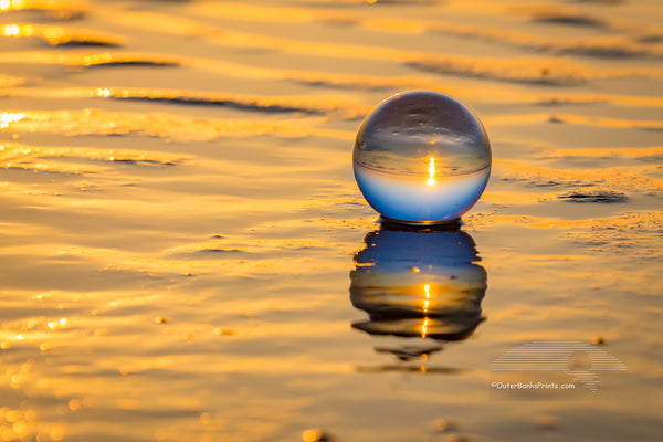Crystal ball and it's reflection at sunrise on the beach at the Outer Banks , NC.