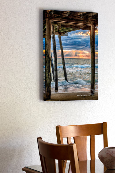20"x30" x1.5" stretched canvas print hanging in the dining room of Rays of sun light streak through the clouds at Avalon Fishing Pier in Kill Devil Hills on the Outer Banks.