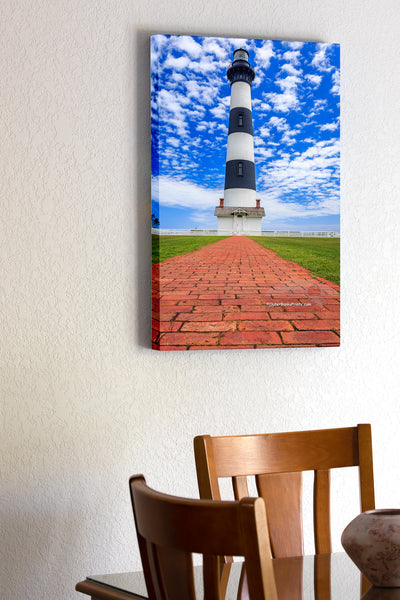 20"x30" x1.5" stretched canvas print hanging in the dining room of Bodie Island Lighthouse red brick walkway leading up to the lighthouse and a blue sky with puffy white clouds.