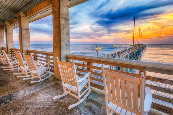 A line of rocking chairs looking out over Jennette's Pier in Nags Head, NC.
