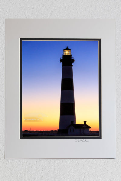 8 x 10 luster print in a 11 x 14 ivory and black double mat of The first rays of warm orange light to peek over the horizon at Bodie Island Lighthouse.