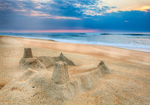 The sun rising behind a sandcastle on the beach at Kill Devil Hills on the Outer Banks of North Carolina.