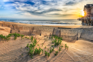 Sand dune and sand fence at sunrise next to  Jennette's Pier in Nags Head on the Outer Banks of NC.