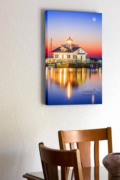 20"x30" x1.5" stretched canvas print hanging in the dining room of Roanoke Marshes Lighthouse in Manteo North Carolina with the moon setting behind it.   The sun is just brightening the sky and reflecting in the calm waters of Shallowbag Bay.