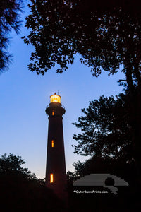 Trees frame  the Currituck Beach Lighthouse at twilight in Corolla on the Outer Banks.