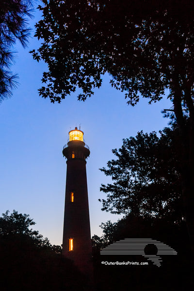 Trees frame  the Currituck Beach Lighthouse at twilight in Corolla on the Outer Banks.