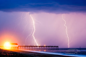Lightning storm at Kitty Hawk Fishing Pier NC. The yellow light on the pier is a powerful street light shining on to the beach.