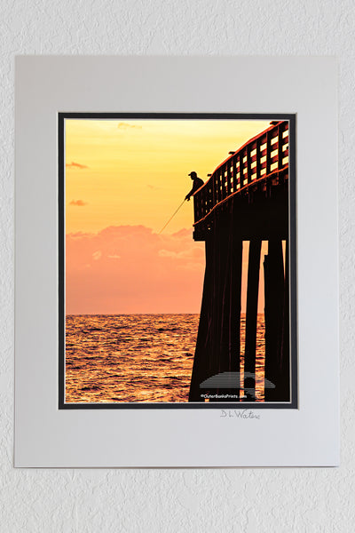 8 x 10 luster print in a 11 x 14 ivory and black double mat of Picture of a fishermen silhouetted at the end of Kitty Hawk Pier.
