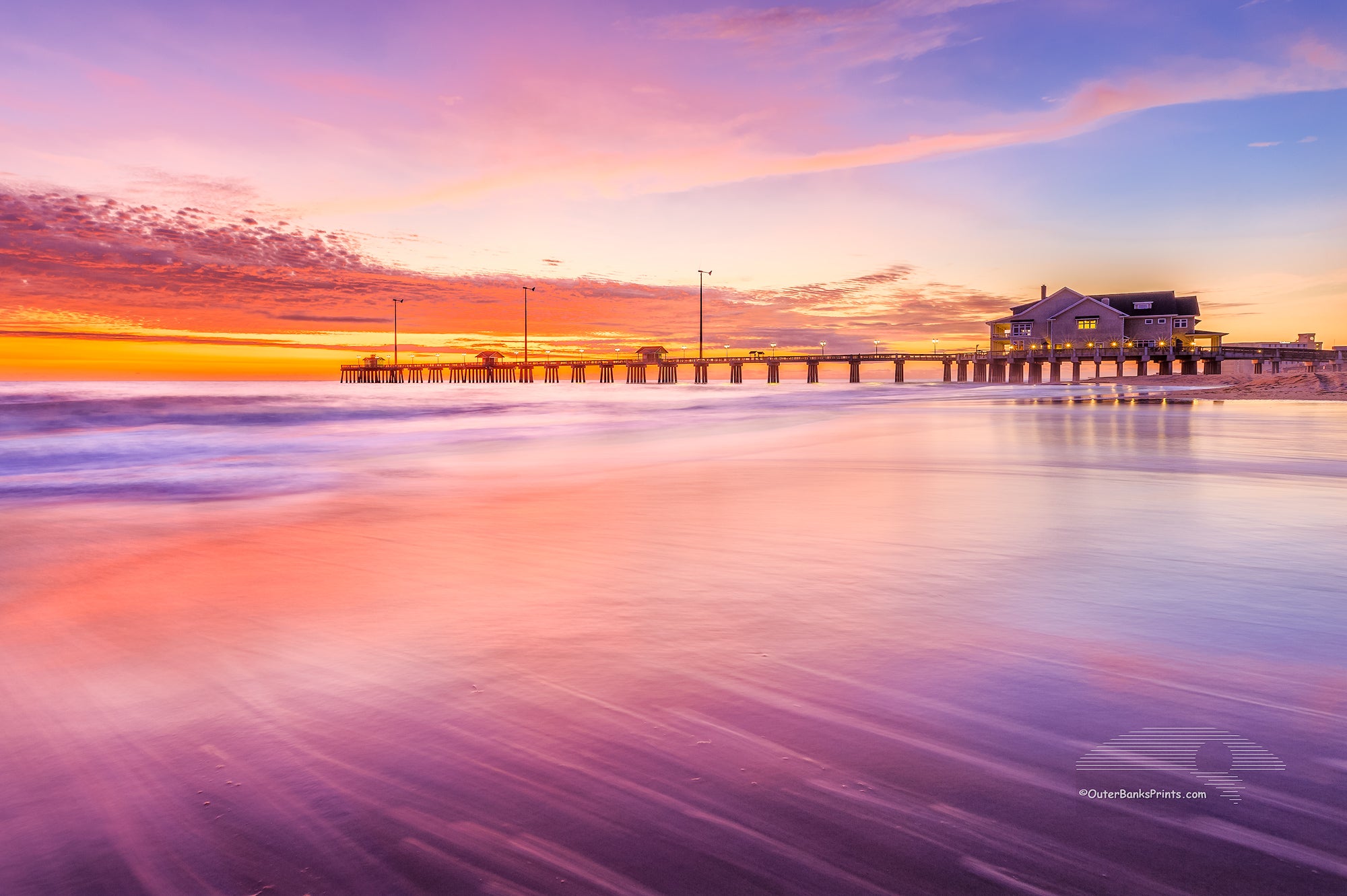 Sunrise colors reflect off shallow waves as they slide back into the sea at Jennette's Pier.