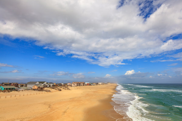 Photograph of Nags Head beach taken from Jennette's Pier on a sunny day with scattered clouds.