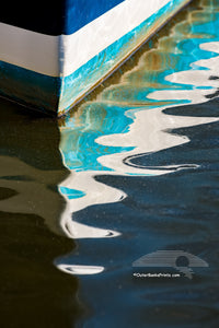 Pattern of light, shadow, and color in the reflection of the bow of a fishing boat in Wancheese Harbor on the Outer Banks of NC.
