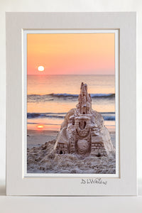 4 x 6 luster print in a 5 x 7 ivory mat of The sun rises over an elaborate sand castle in Corolla on the Outer Banks NC.