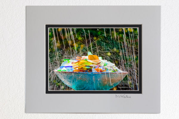 5 x 7 luster prints in a 8 x 10 ivory and black double mat of  This beach glass was found on the beaches of the Outer Banks. It is just a small part of our collection. Broken bottles are smoothed and tumbled by the surf and sand before it becomes sea glass. I photographed this in my backyard using an oscillating sprinkler.The slow shutter speed and back light made of the sprinkler look like raindrops.