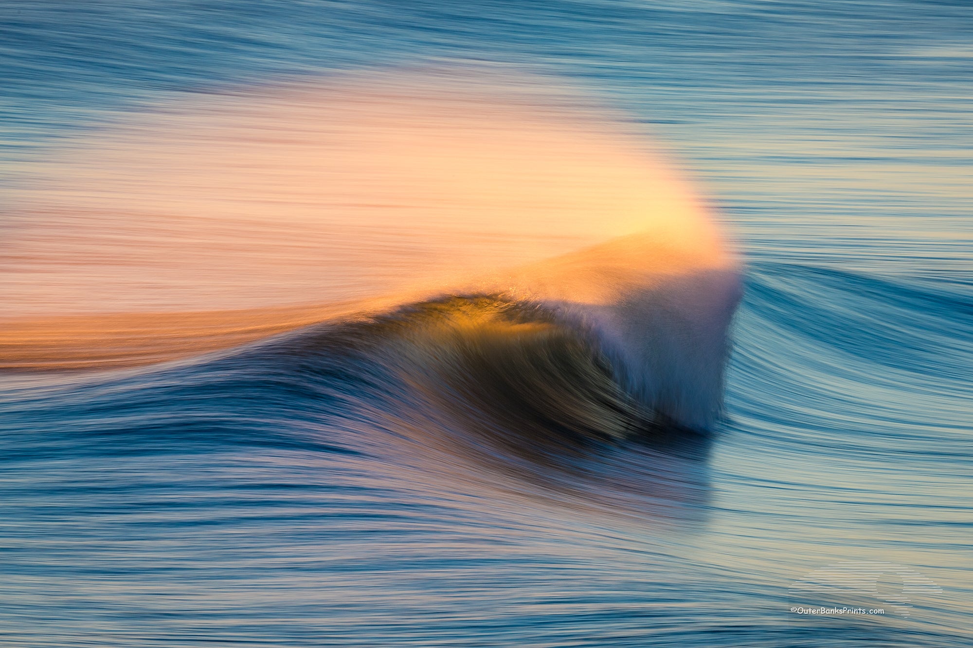 Windblown spray from the surf, back lit by the rising sun in Kill Devil Hills on the Outer Banks of North Carolina.