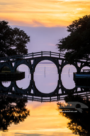 A still sunset reflection of the wooden bridge between the Whale Head Club and Currituck Beach Lighthouse in Corolla on the Outer Banks of NC.