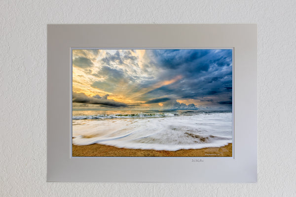 3 x 19 luster print in 18 x 24 ivory ￼￼mat of Sunrise and clouds with light rays poking through stormy skies over Kill Devil Hills beach on the Outer Banks of NC.
