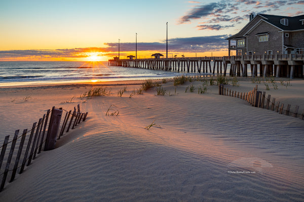 Early morning light stretches across the dunes at Jennette's Pier in Nags Head on the Outer Banks of North Carolina.