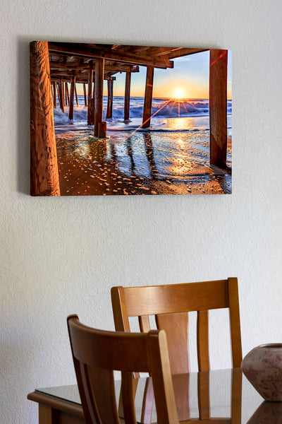 20"x30" x1.5" stretched canvas print hanging in the dining room of The sun peeking above horizon at Nags Head Fishing Pier Outer Banks, NC.
