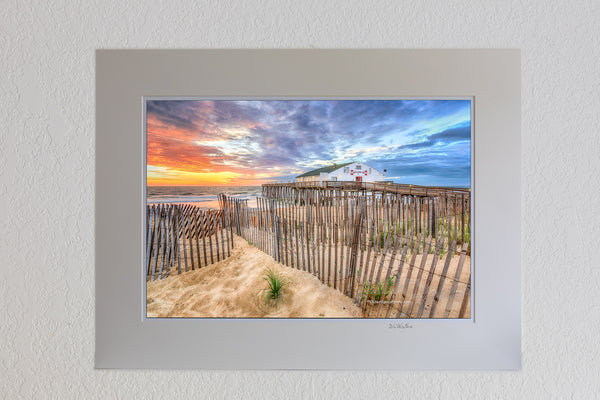 13 x 19 luster print in 18 x 24 ivory ￼￼mat of Sand fence at sunrise in front of Kitty Hawk Fishing Pier on the Outer Banks.