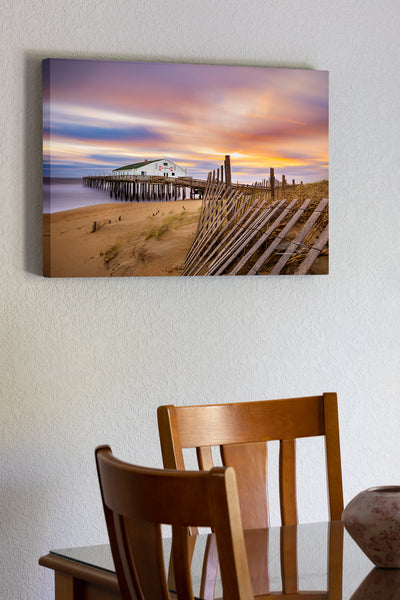 20"x30" x1.5" stretched canvas print hanging in the dining room of Long exposure of sand fence, sunrise, clouds, and Kitty Hawk Fishing Pier on the Outer Banks of NC.