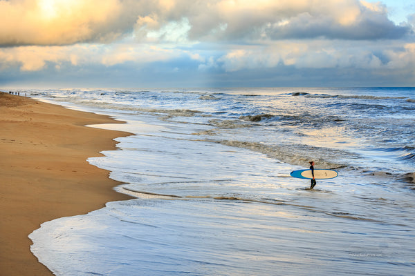 Picture of Nags Head beach. an early-morning surfer wadding into the ocean.