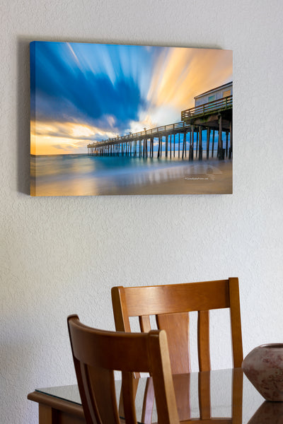 20"x30" x1.5" stretched canvas print hanging in the dining room of Long exposure showing the motion of the clouds and surf at Kitty Hawk Fishing Pier sunrise on the Outer Banks of NC.