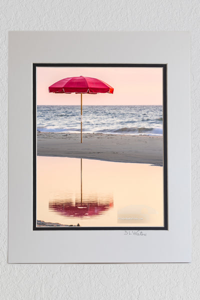8 x 10 luster print in a 11 x 14 ivory and black double mat of Lonely umbrella reflected in a tide pool at a Duck, NC beach on the Outer Banks.