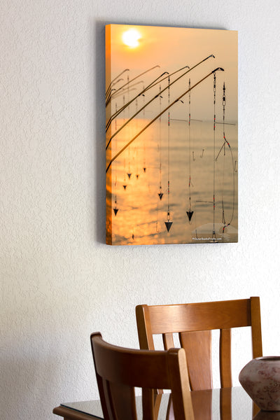 20"x30" x1.5" stretched canvas print hanging in the dining room of A line of fishing poles silhouetted against the sun at Avalon pier Kill Devil Hills.