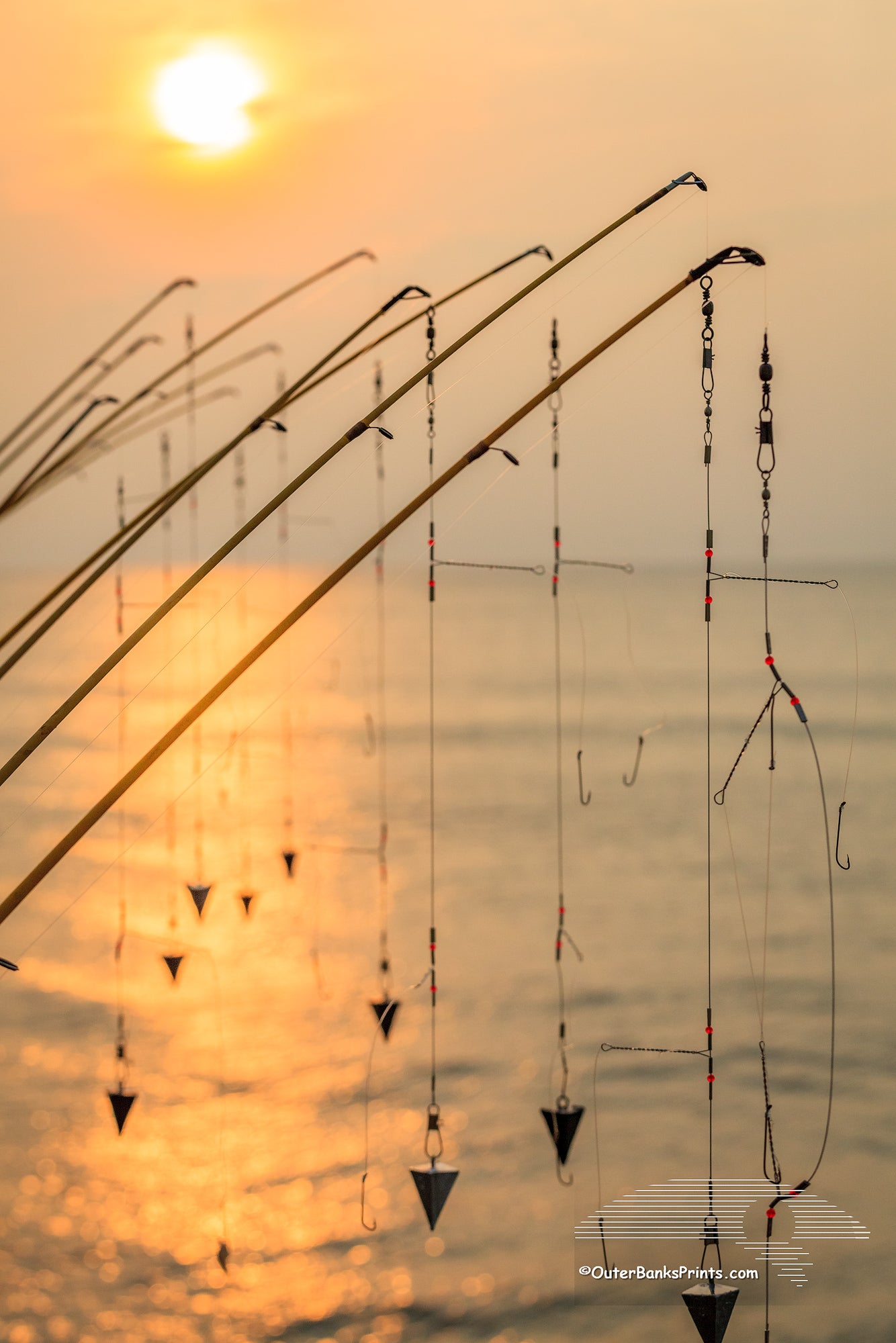 A line of fishing poles silhouetted against the sun at Avalon pier Kill Devil Hills.