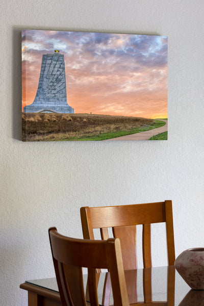20"x30" x1.5" stretched canvas print hanging in the dining room of Sunrise cloudy sky create a backdrop behind the Wright Brothers Memorial in Kill Devil Hills North Carolina.
