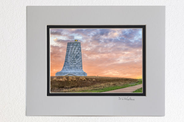 8 x 10 luster print in a 11 x 14 ivory and black double mat of Sunrise cloudy sky create a backdrop behind the Wright Brothers Memorial in Kill Devil Hills North Carolina.