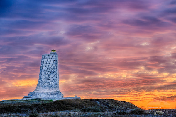 Sunrise cloudy sky create a backdrop behind the Wright Brothers Memorial in Kill Devil Hills North Carolina.