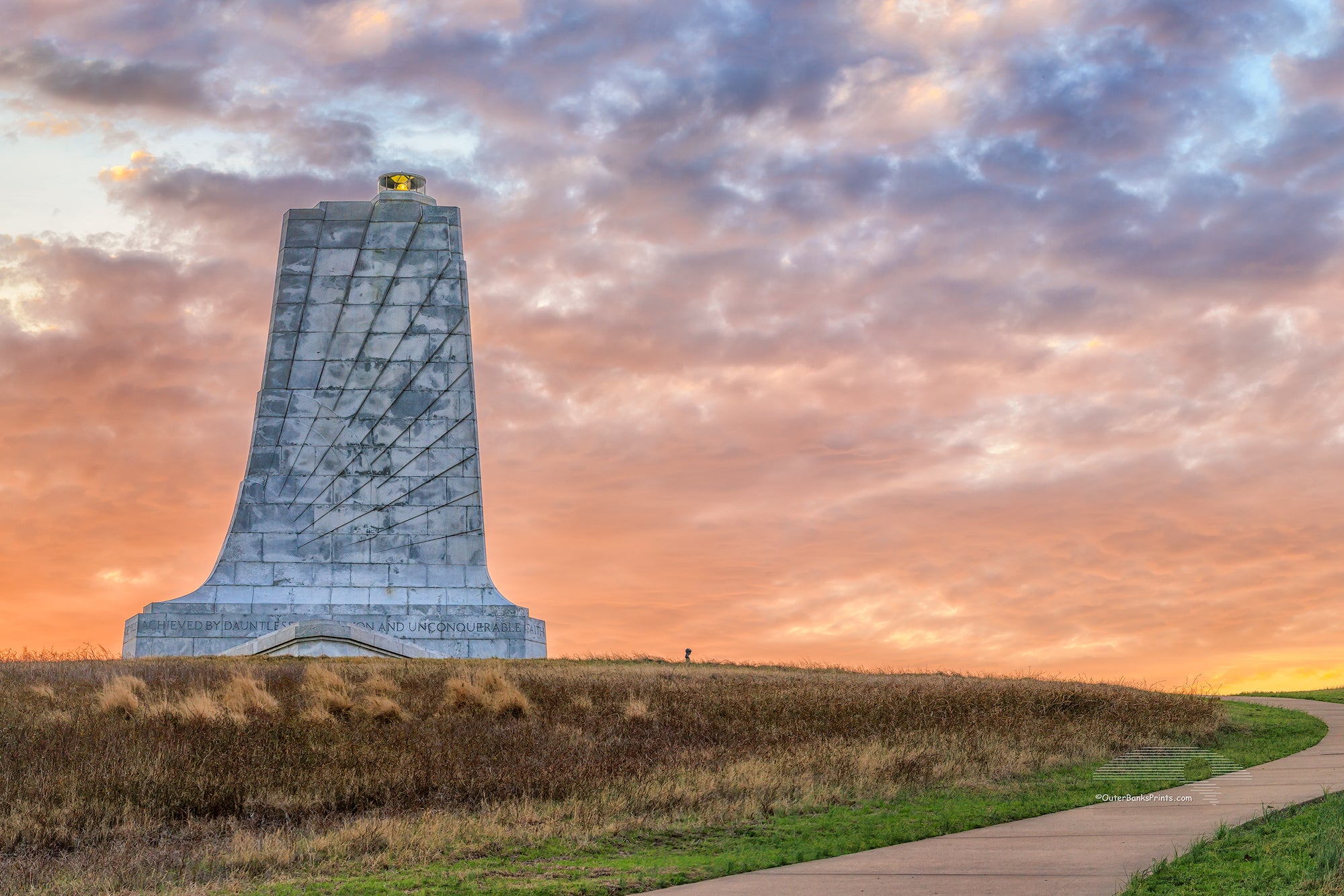 Sunrise cloudy sky create a backdrop behind the Wright Brothers Memorial in Kill Devil Hills North Carolina.