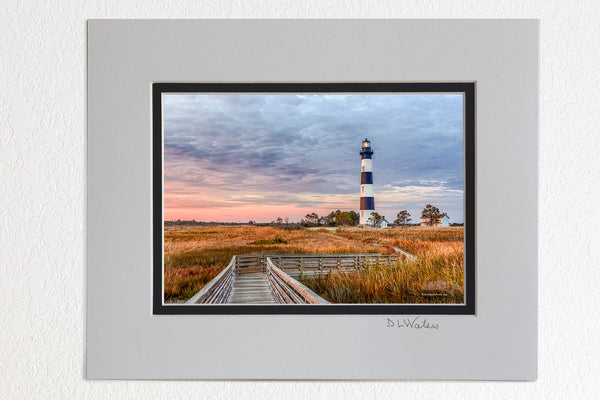 5 x 7 luster prints in a 8 x 10 ivory and black double mat of A walkway through the marsh leading to Bodie Island Lighthouse at sunrise.